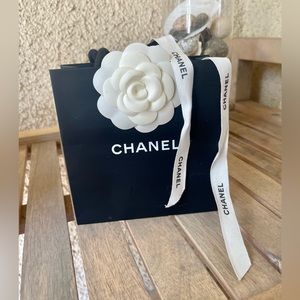 Small Chanel shopping bag with chanel ribbon and classes white flower.